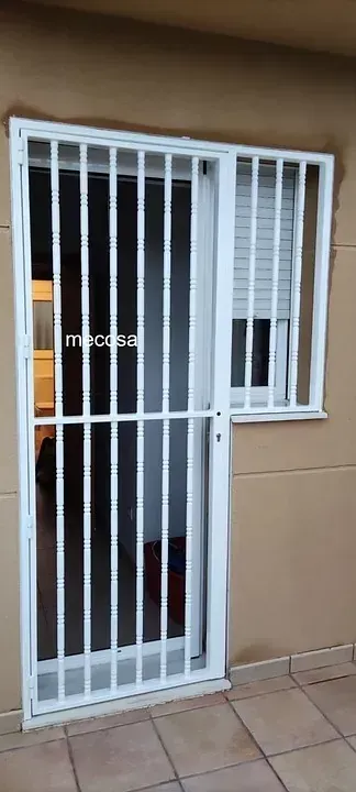 Una puerta blanca con una ventana y una valla alrededor.