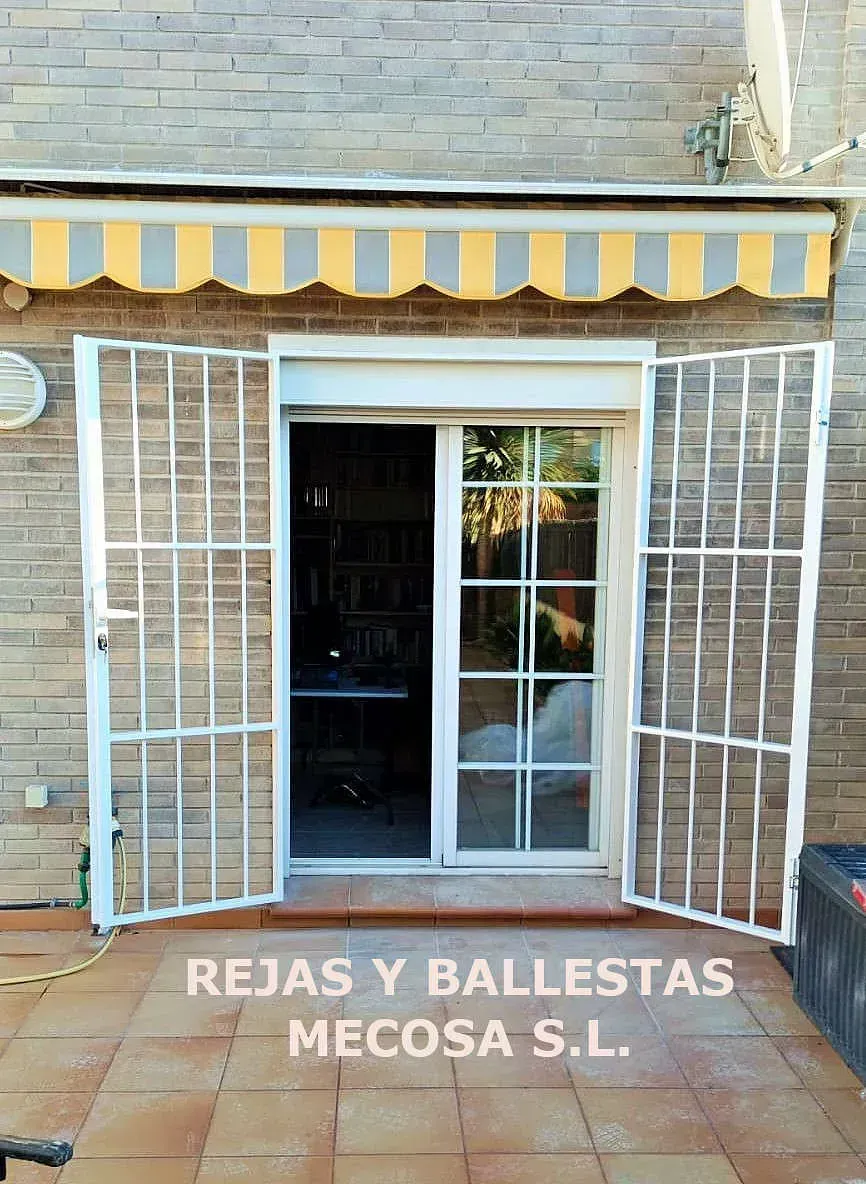 Una imagen de una puerta corrediza de vidrio con un toldo amarillo y blanco y las palabras rejas y ballestas mecosa sl