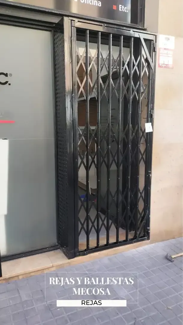 Una puerta negra está situada delante de un edificio.