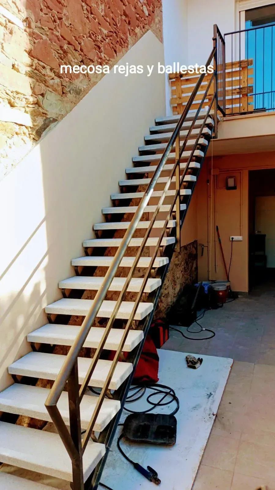 Se está construyendo una escalera con barandilla metálica en un edificio.