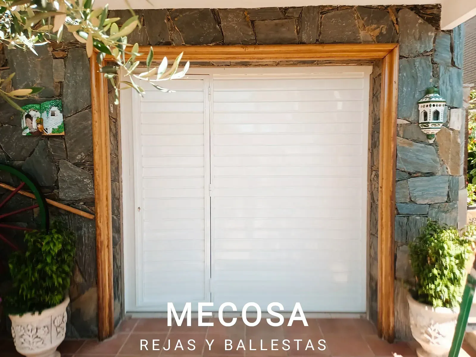 Una puerta de garaje blanca con marco de madera frente a una pared de piedra.