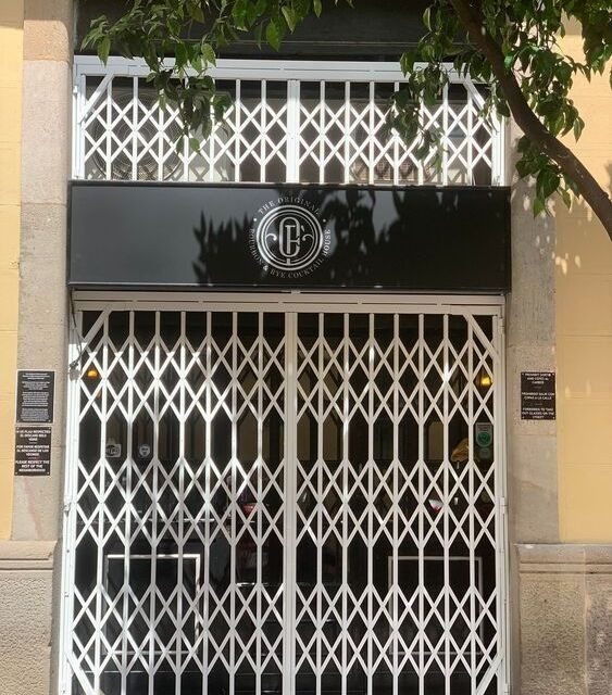 Un escaparate con un cartel negro y una puerta de metal.