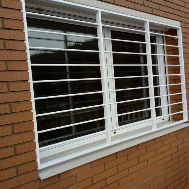 Un edificio de ladrillo con una ventana blanca con rejas alrededor.