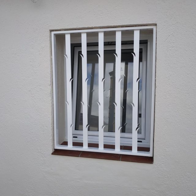 Una ventana con una valla metálica blanca alrededor.
