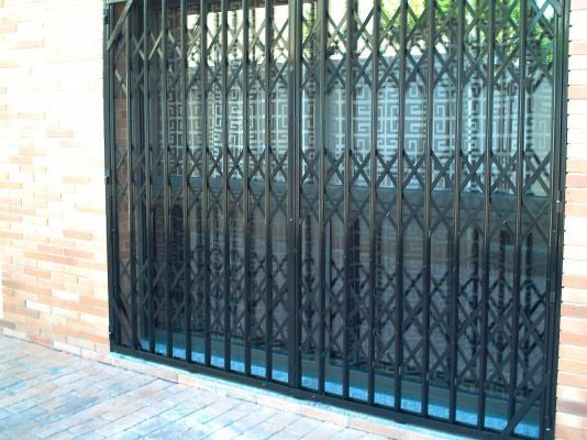 Una puerta de metal negro está apoyada sobre una pared de ladrillos.