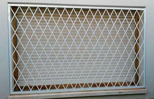 Una valla metálica blanca se encuentra delante de una ventana.