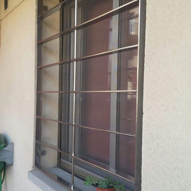 Una ventana con una reja alrededor y una planta en maceta delante de ella.