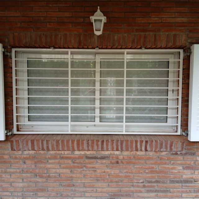 Una pared de ladrillos con una ventana con rejas.