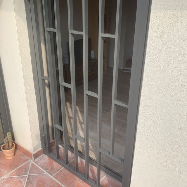 Una puerta con una reja de metal está abierta a una habitación.