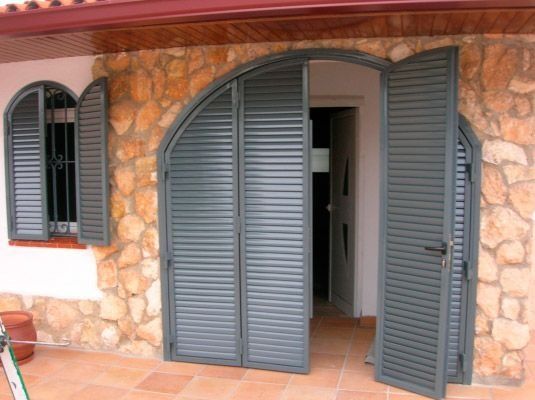 Un edificio de piedra con persianas en las puertas y ventanas.