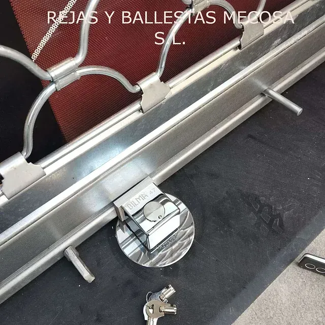 Un primer plano de una puerta de acero inoxidable con las palabras rejas y ballestas mecosa sl en la parte inferior.