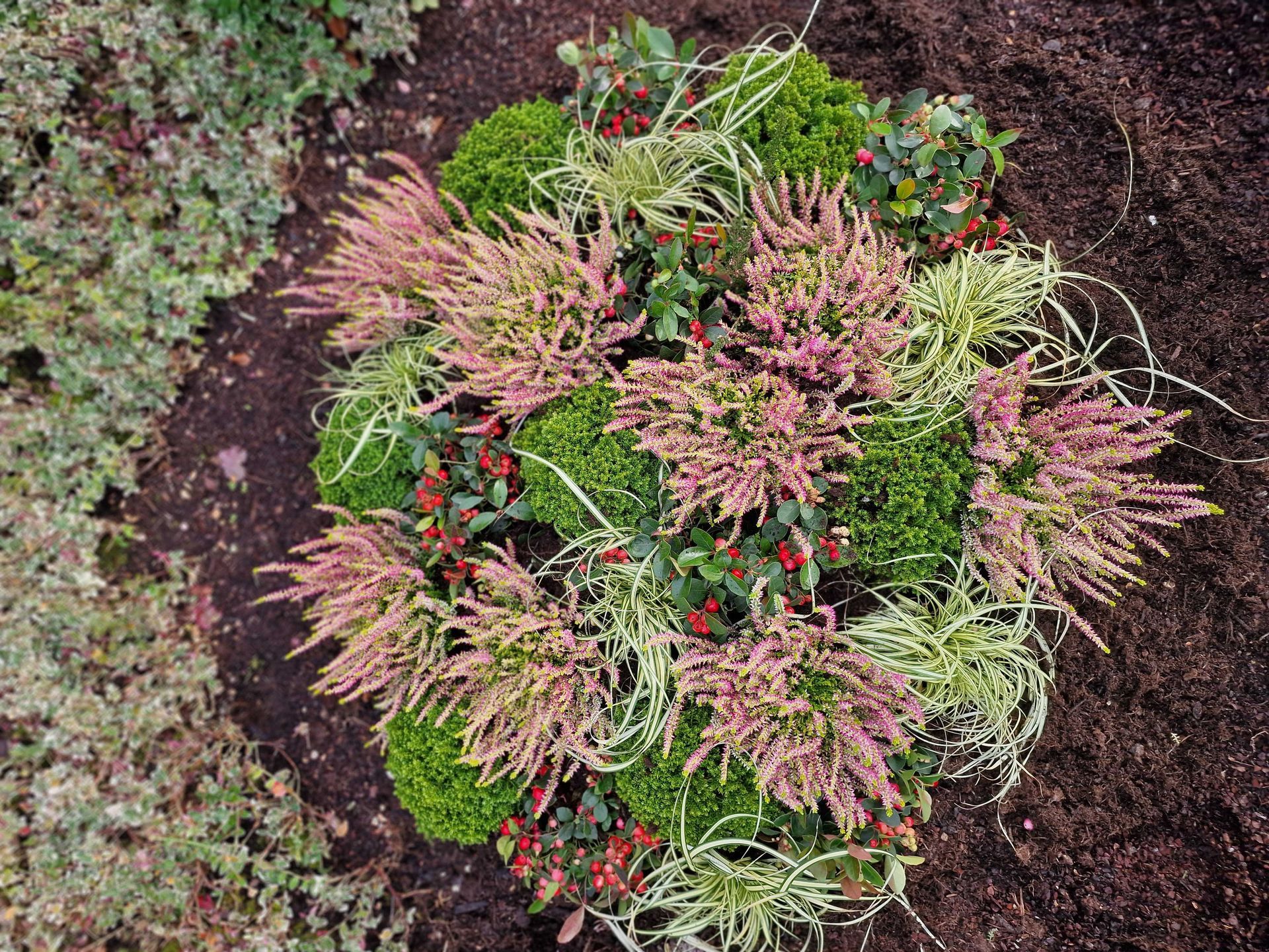 Floristisches Arrangement für Gräber, mit gedeckten Blumenfarben und natürlichen Elementen.