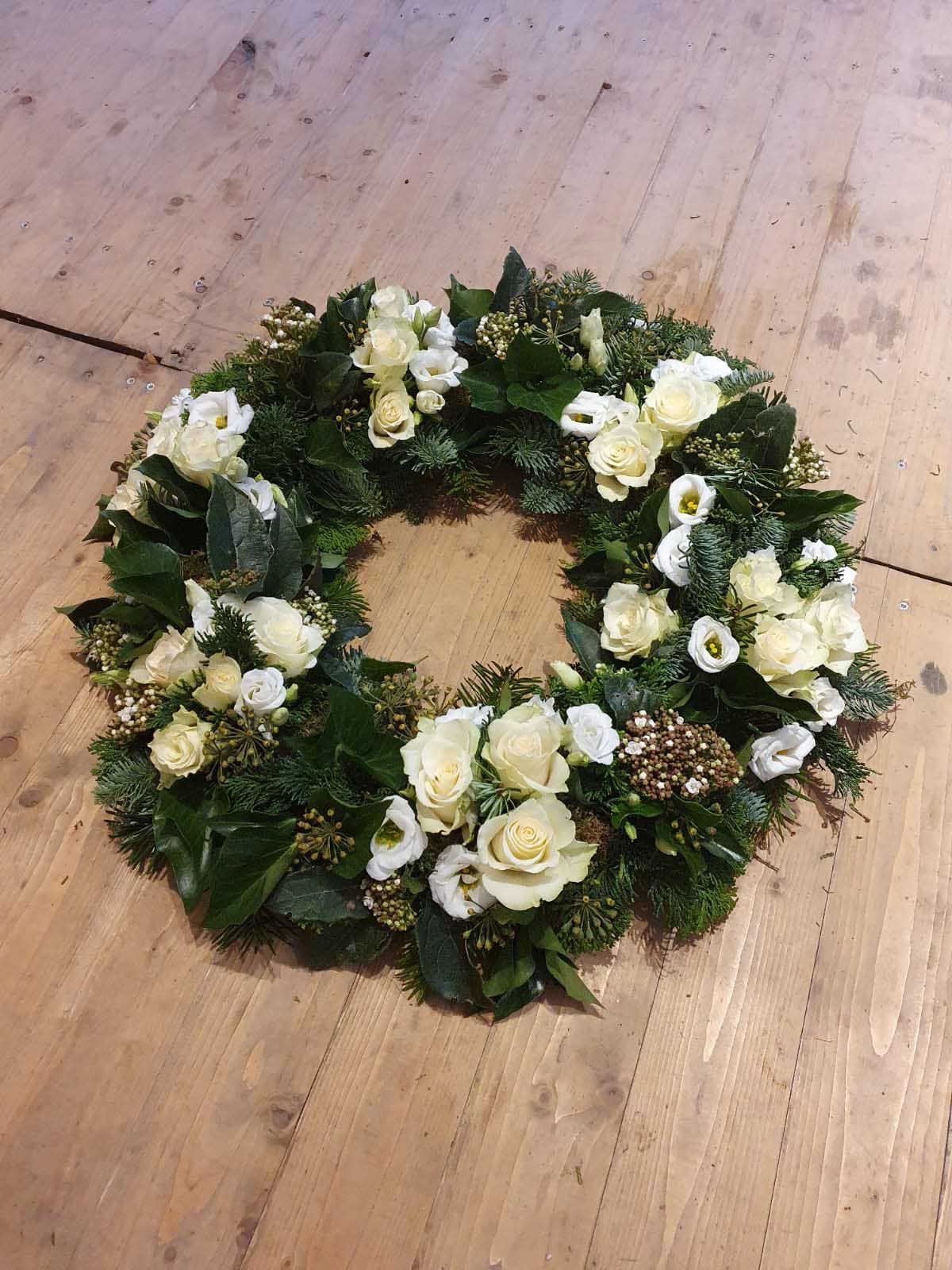 Runder Blumenstrauß aus rosa Rosen und weißen Lilien, mit grünem Eukalyptus verziert.