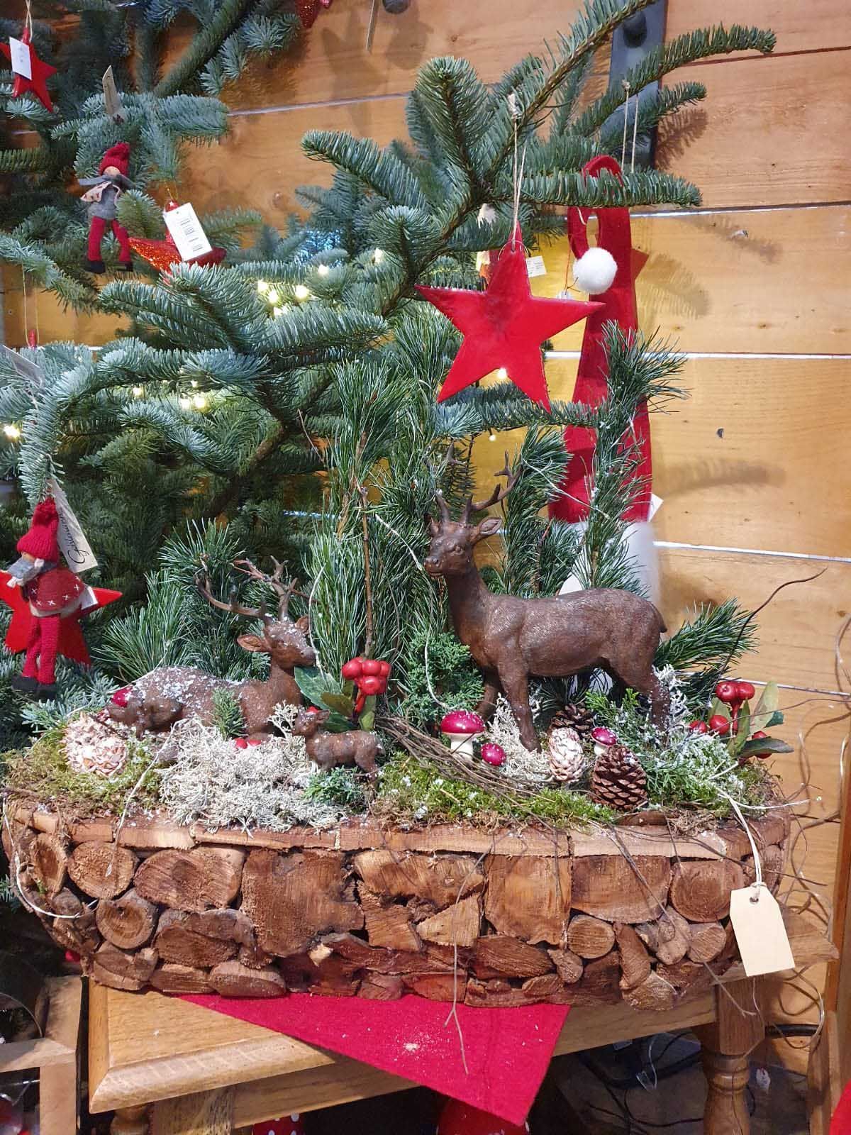 Festliches Gesteck mit Tannenzweigen, Zapfen und roten Beeren, dekoriert mit weihnachtlichen Elementen.