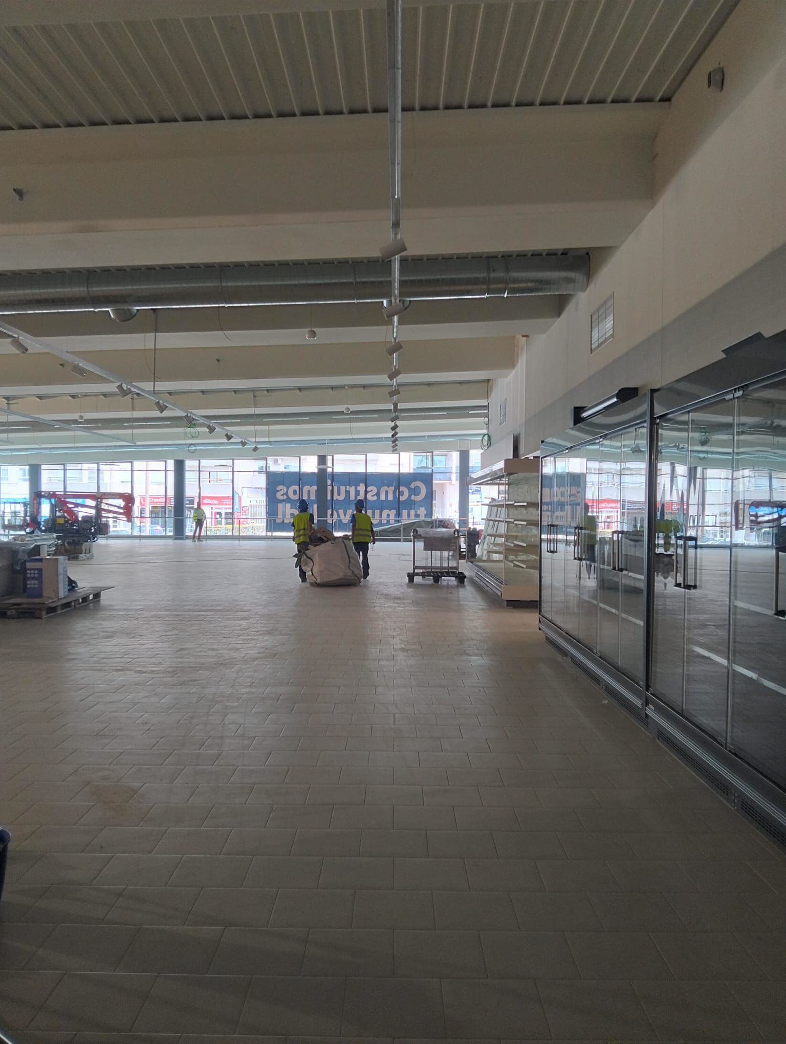 Interior del taller: estantes de madera, herramientas, banco de trabajo, ventana, luz solar.