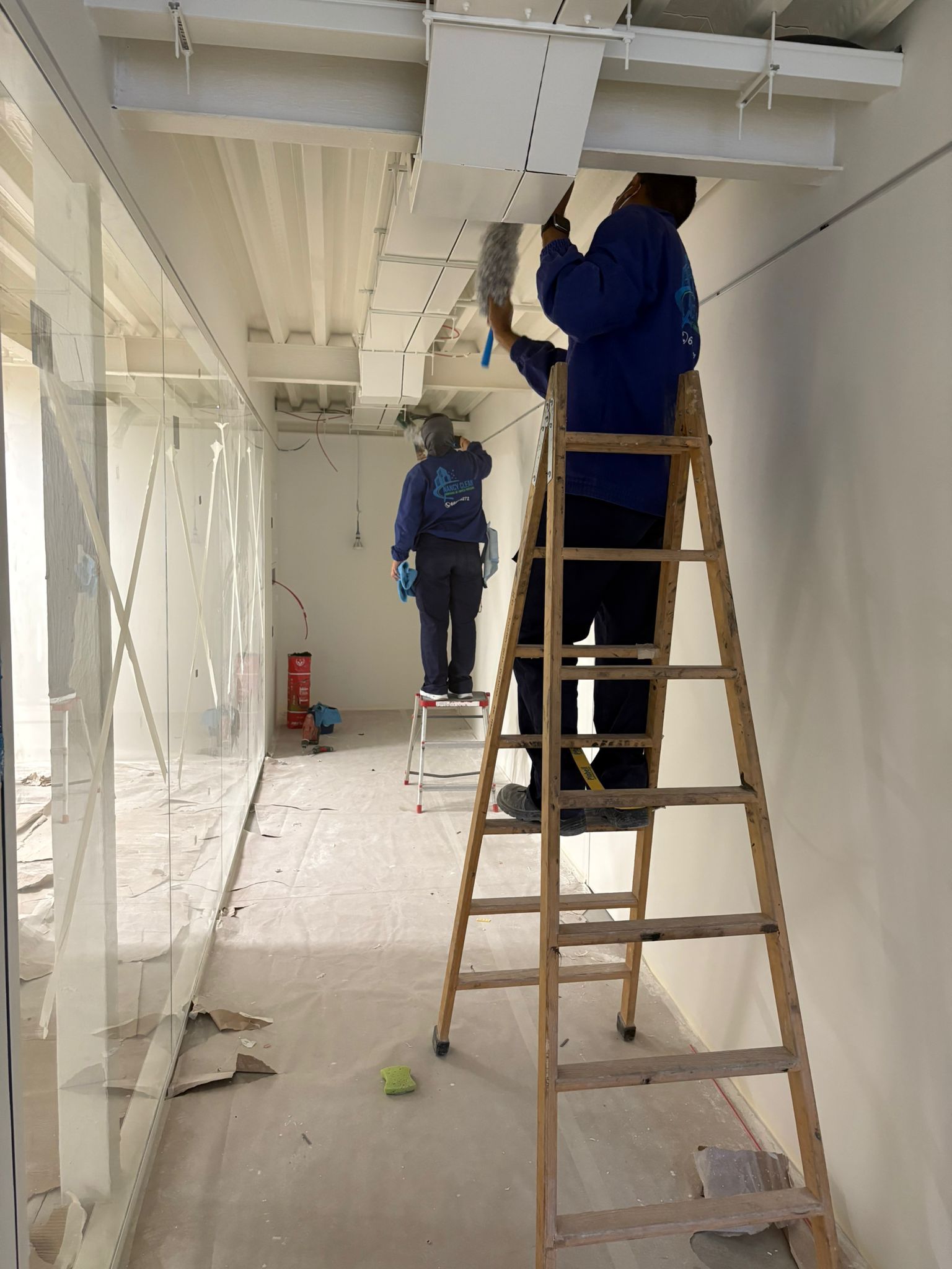 Mujer con mascarilla desinfectando su escritorio de oficina con una botella de spray y una toallita.