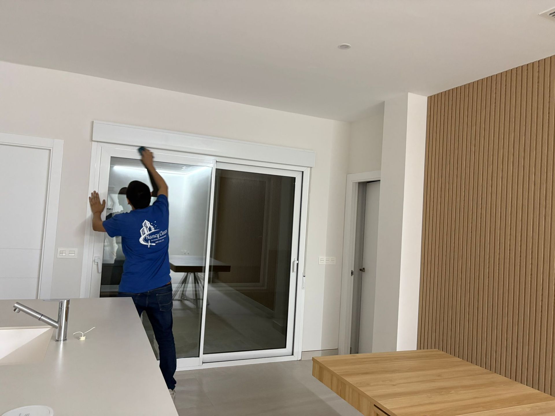 Persona que usa guantes amarillos limpiando una estufa negra con un paño amarillo en una cocina.