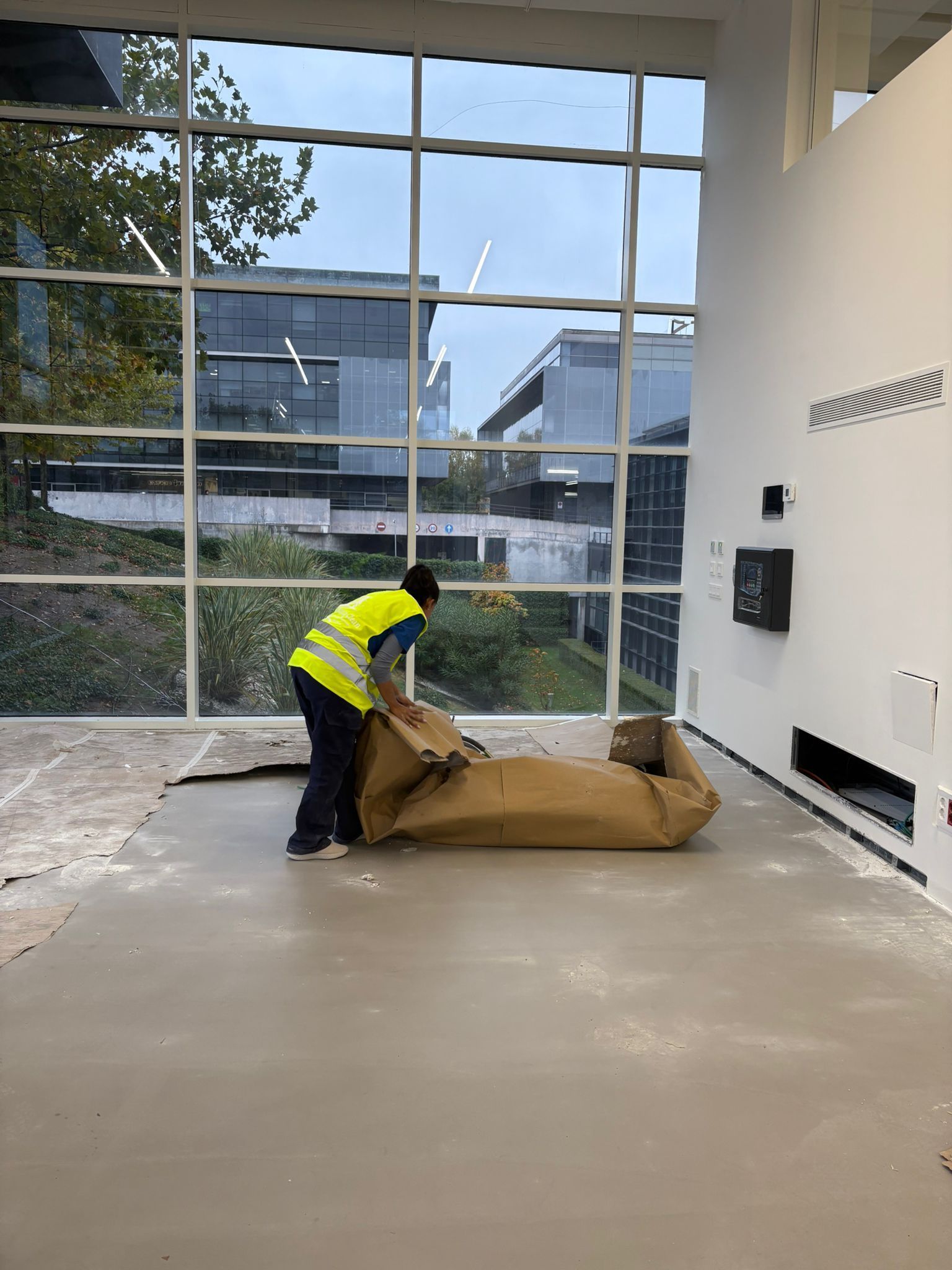 Mujer con mascarilla desinfectando su escritorio de oficina con una botella de spray y una toallita.