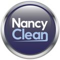 Un botón metálico circular con el texto "Nancy Clean" en blanco y azul claro sobre un fondo azul oscuro.