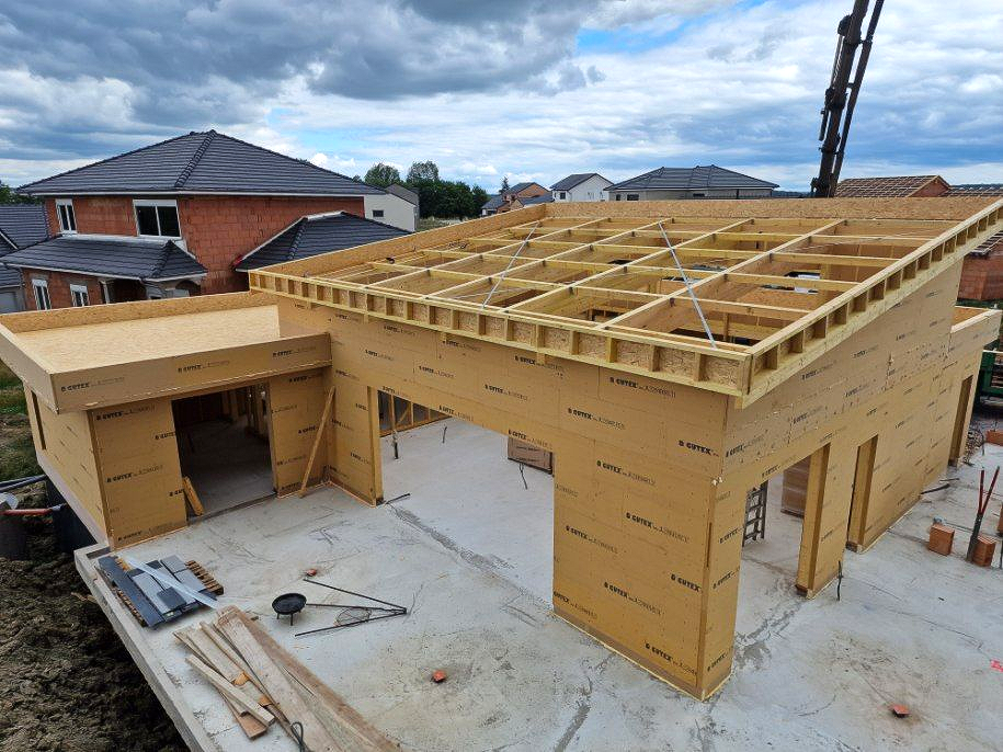La charpente en bois d'une maison en construction se détache sur un ciel bleu.