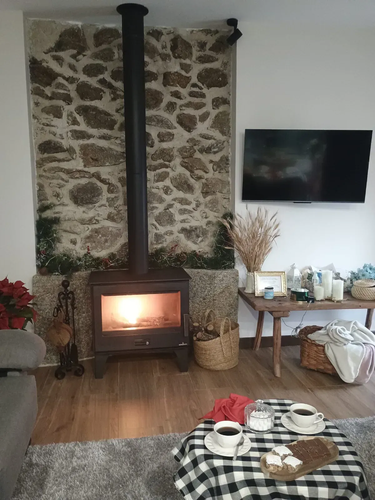 Acogedora sala de estar con estufa de leña encendida, pared de piedra.