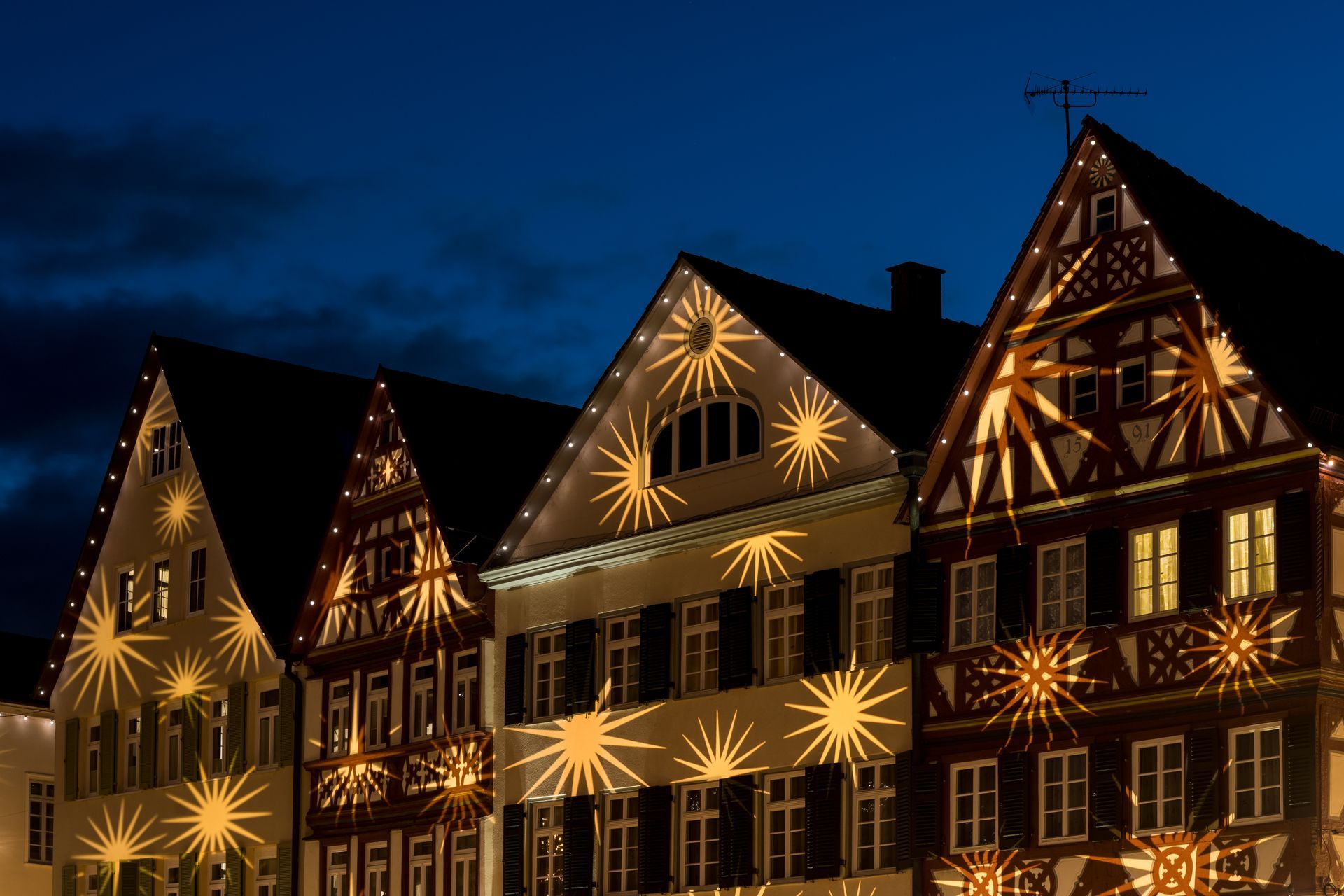 Ein Gourmetgericht auf einem weißen Teller an einem Restauranttisch, der mit Weingläsern, Wasser und Brot gedeckt ist.