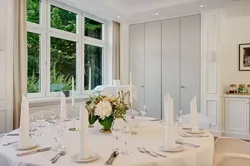 Ein runder Esstisch mit großem Fenster und einem in neutralen Farbtönen gehaltenen Raum.