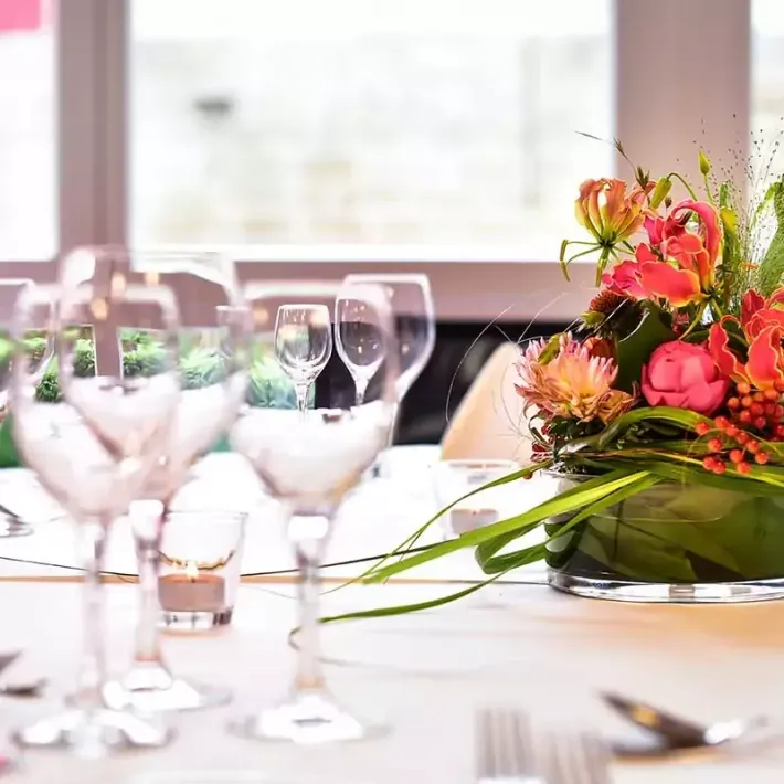 Tischdekoration mit Blumenschmuck und Glaswaren, weicher Fokus.