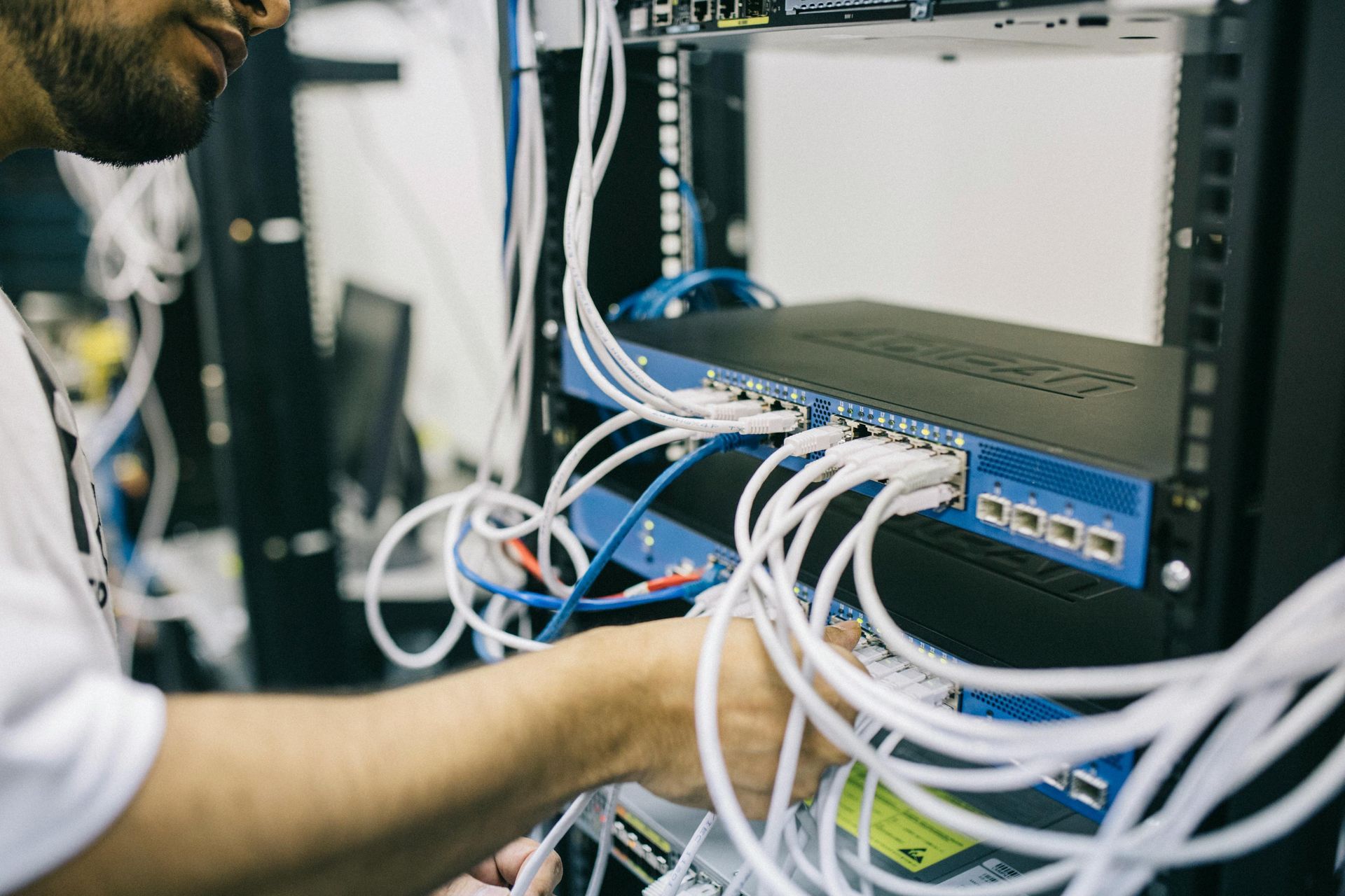 Mann arbeitet in einem Serverraum am Netzwerkserver-Rack und verbindet Kabel.