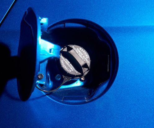 Un coche azul con una tapa de combustible que dice