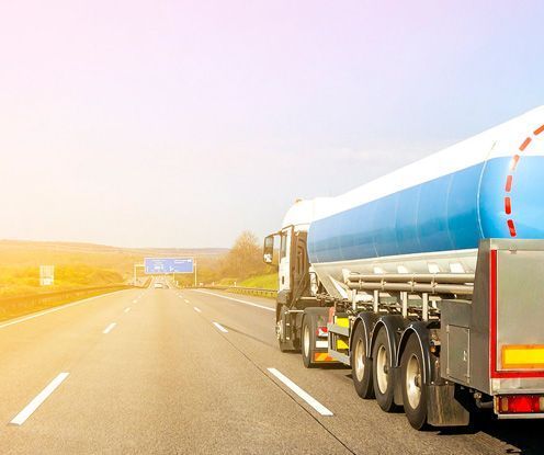 Un camión cisterna azul y blanco circula por una autopista.