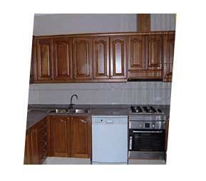 Muebles de cocina de madera con lavavajillas y estufa.