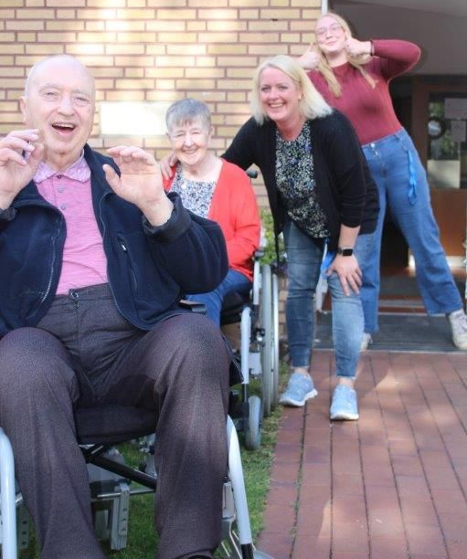 Menschen bei einer Veranstaltung im Freien. Ein Mann erhält einen Geschenkkorb. Andere schauen zu.