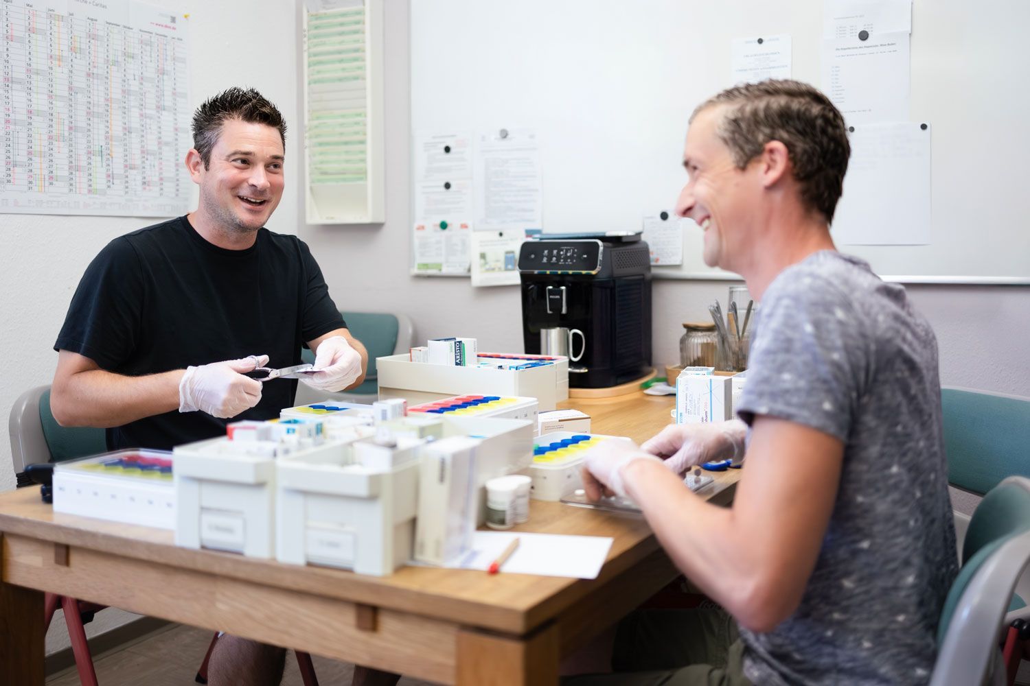 Junge Frau umarmt und lächelt ältere Frau im Rollstuhl an, beide im Freien.
