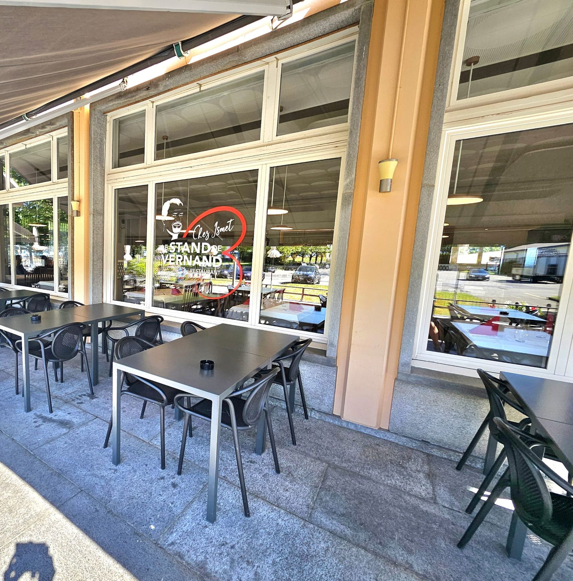 Terrasse de restaurant avec tables et chaises noires sous un auvent.