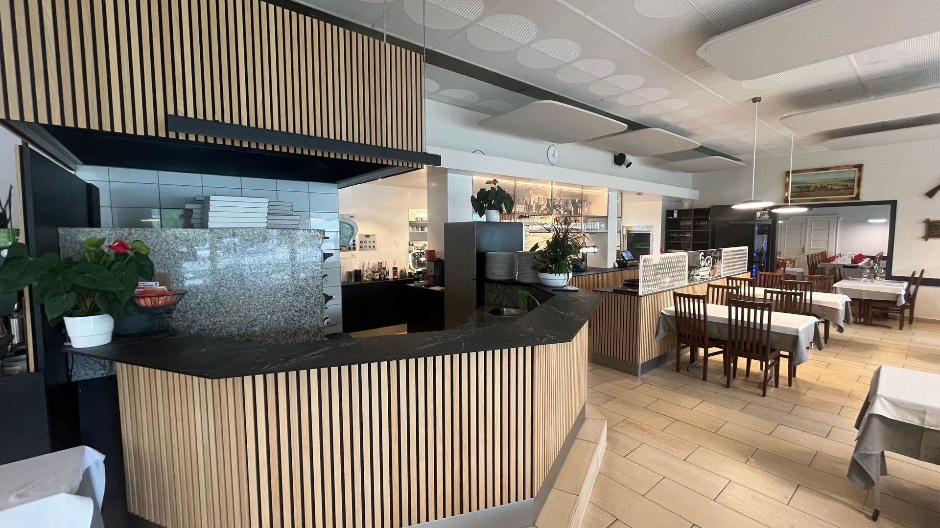 Un restaurant avec des tables et des chaises et un comptoir au milieu de la pièce.