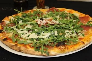 Une pizza avec beaucoup de garnitures est sur une assiette blanche.