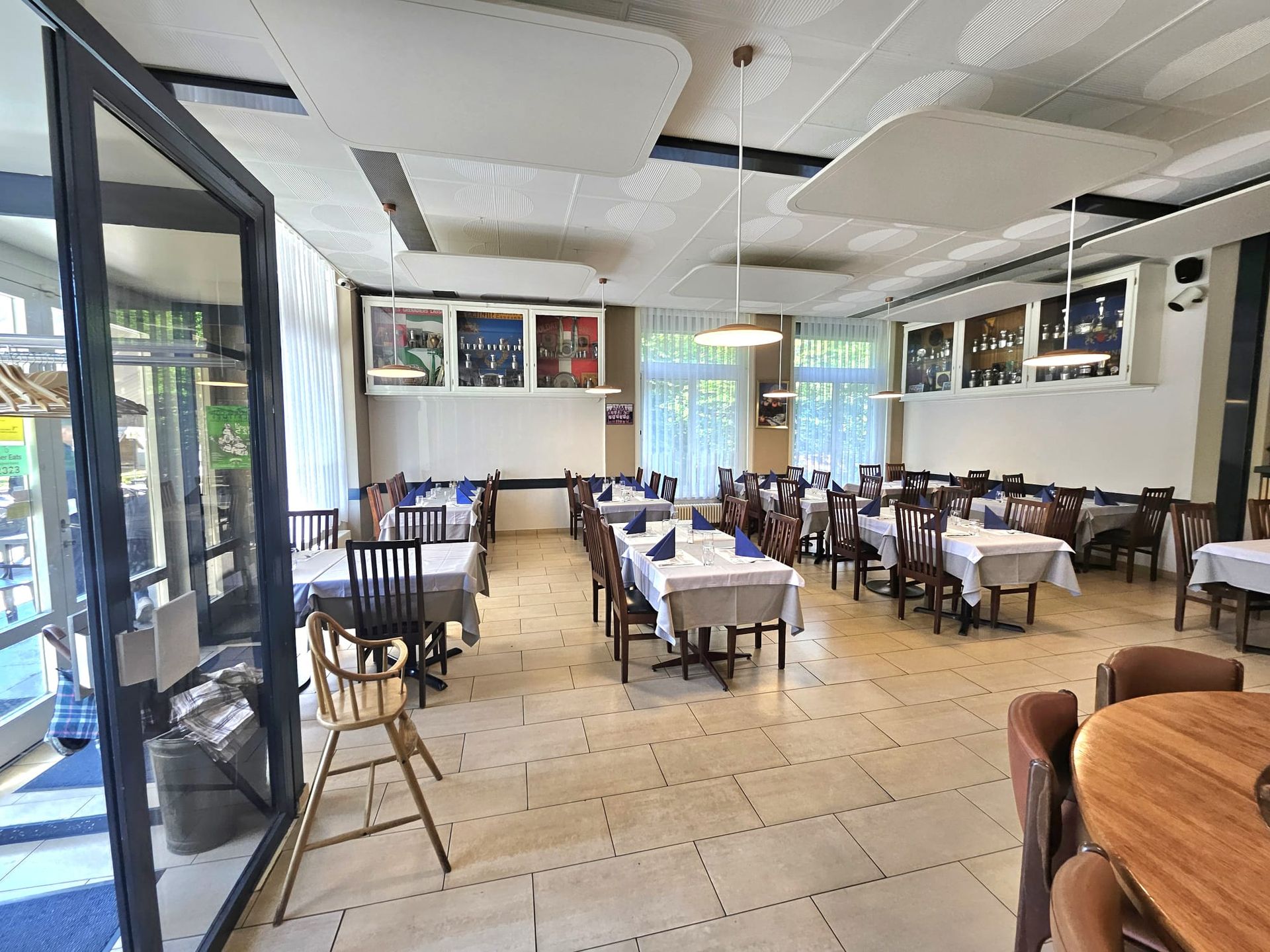 Salle à manger de restaurant avec tables dressées pour les repas, lumière naturelle, couleurs neutres.