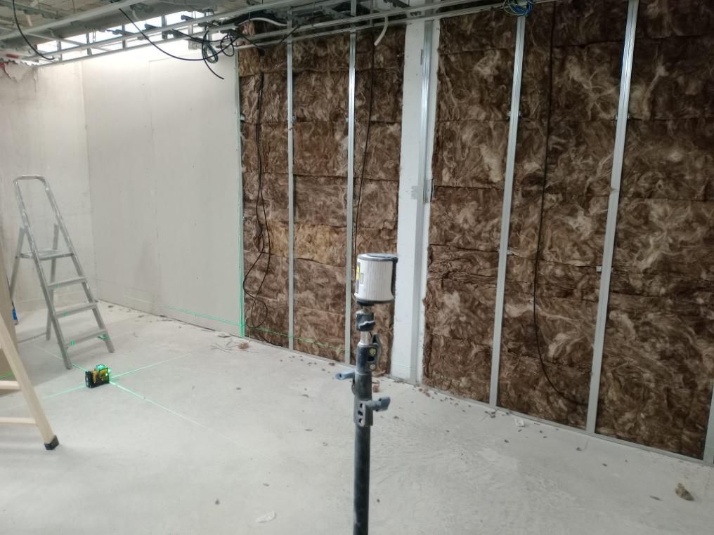 Vista interior de una obra en construcción que muestra la estructura metálica de la pared con aislamiento marrón