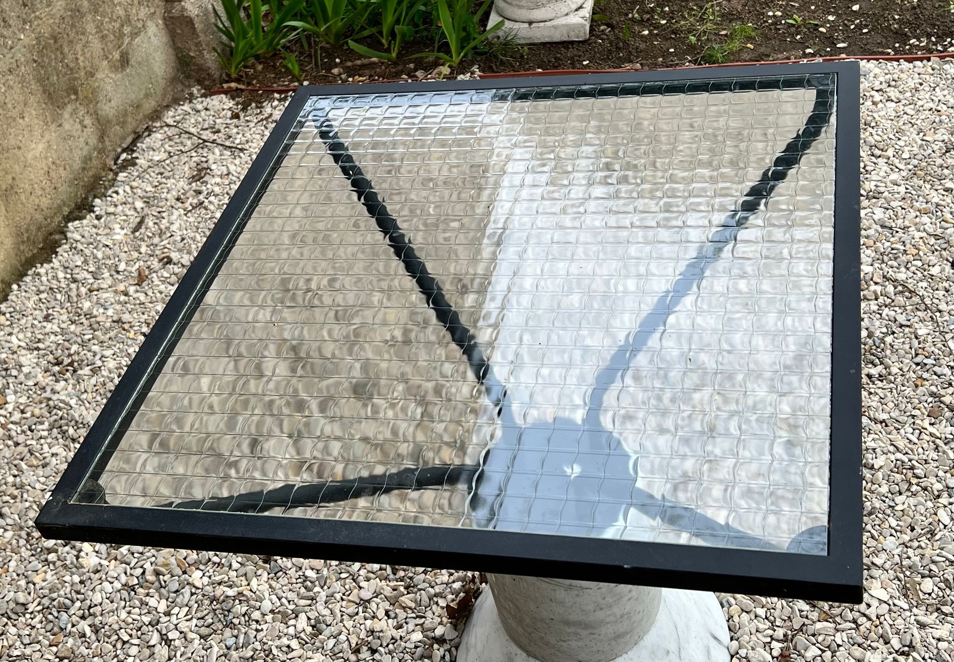 De grandes plaques de verre transparent sont stockées sur un chariot industriel à roulettes, avec d'autres plaques de verre empilées à l'arrière-plan.