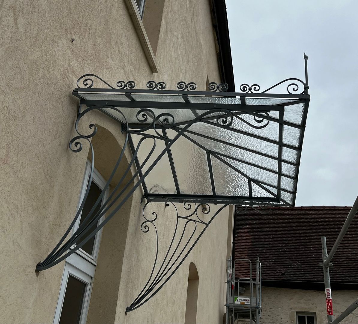 Gros plan sur une main utilisant un coupe-verre pour tracer une ligne sur une vitre contre une règle.