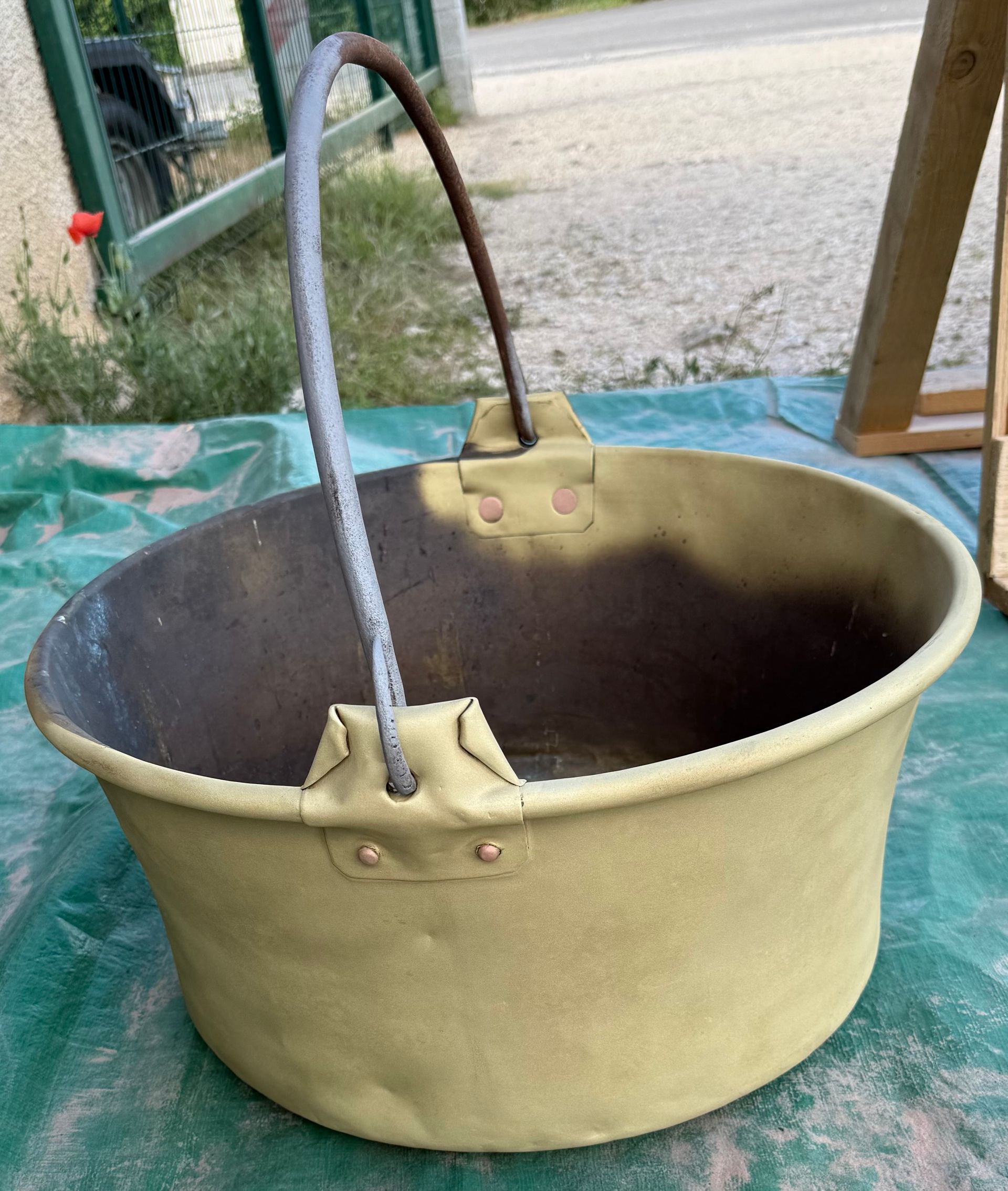 Un portail en métal gris clair usé, présentant des traces de rouille, divisé en quatre panneaux avec un motif de grille décoratif en partie basse.