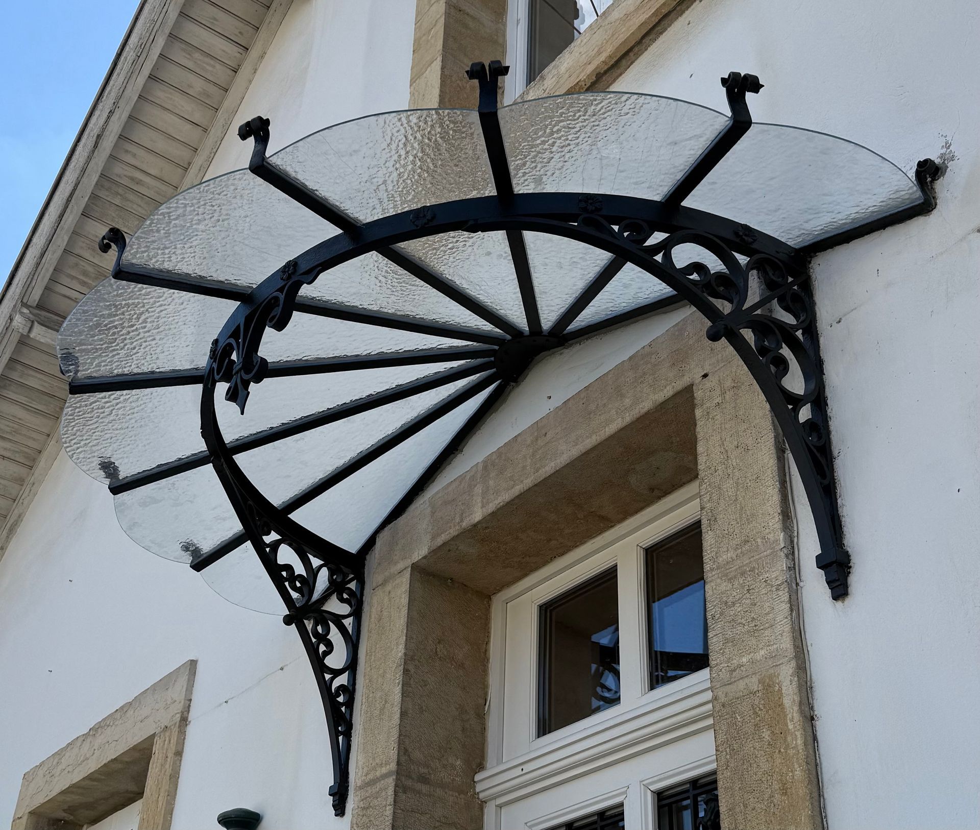 Dans une usine de fabrication, une personne en tenue de travail et gantée de vert vif manipule de grandes vitres.