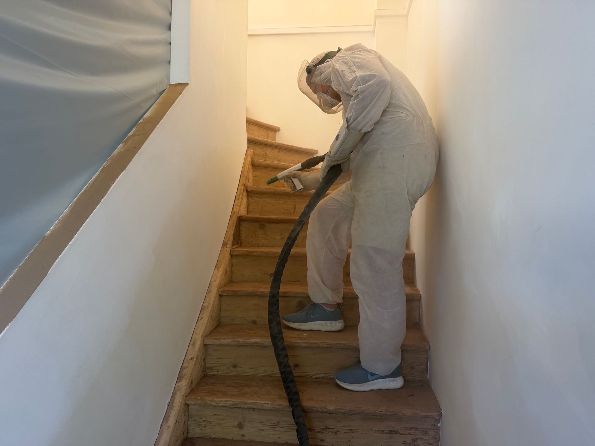Aérogommage d'un escalier Une rambarde en métal gris foncé installée à l'extérieur d'un balcon résidentiel avec un sol carrelé et une fenêtre à cadre en bois.