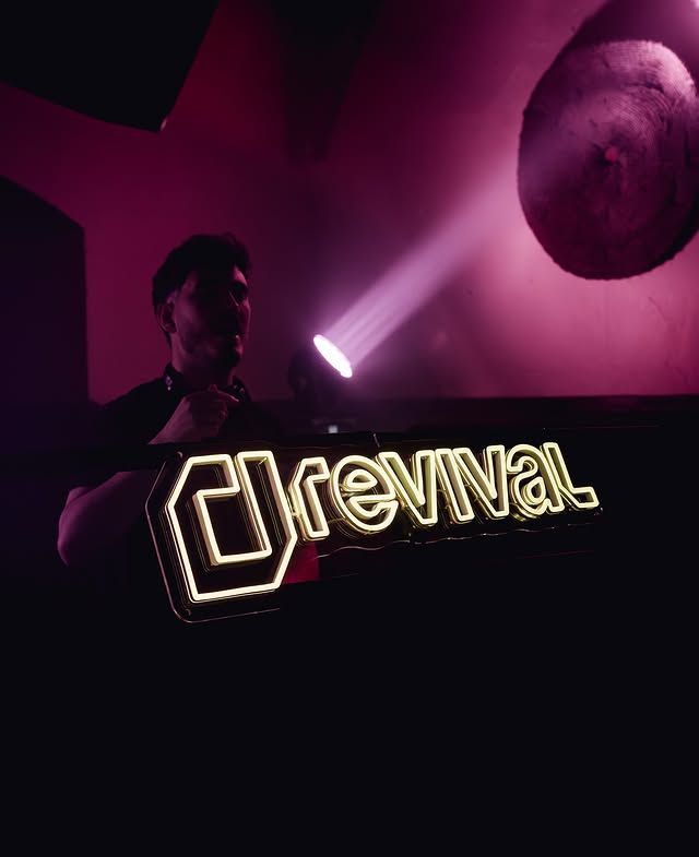 DJ en el escenario, detrás de un letrero luminoso de “Dreival”, bajo luces de discoteca rosas y moradas