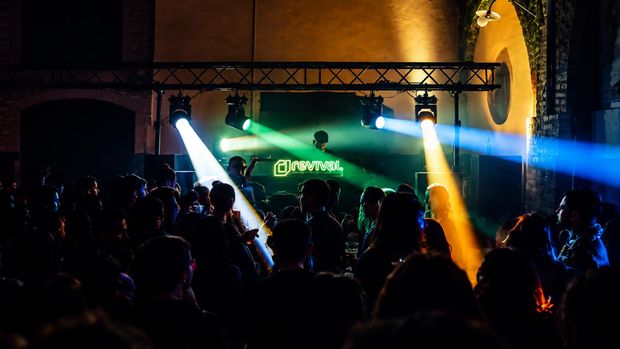 Multitud observando un concierto en directo con luces de escenario verdes y amarillas brillantes por la noche