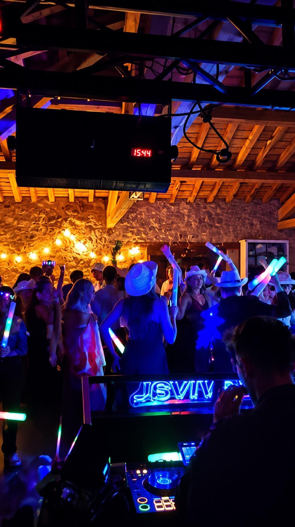 Pista de baile de una discoteca con poca luz, luces de neón de colores y una multitud de cara a la cabina del DJ