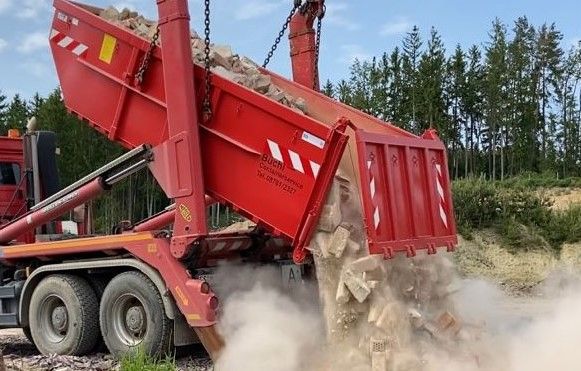 Ein Bagger verlädt Schutt auf einer Abrissbaustelle in einen Muldenkipper.