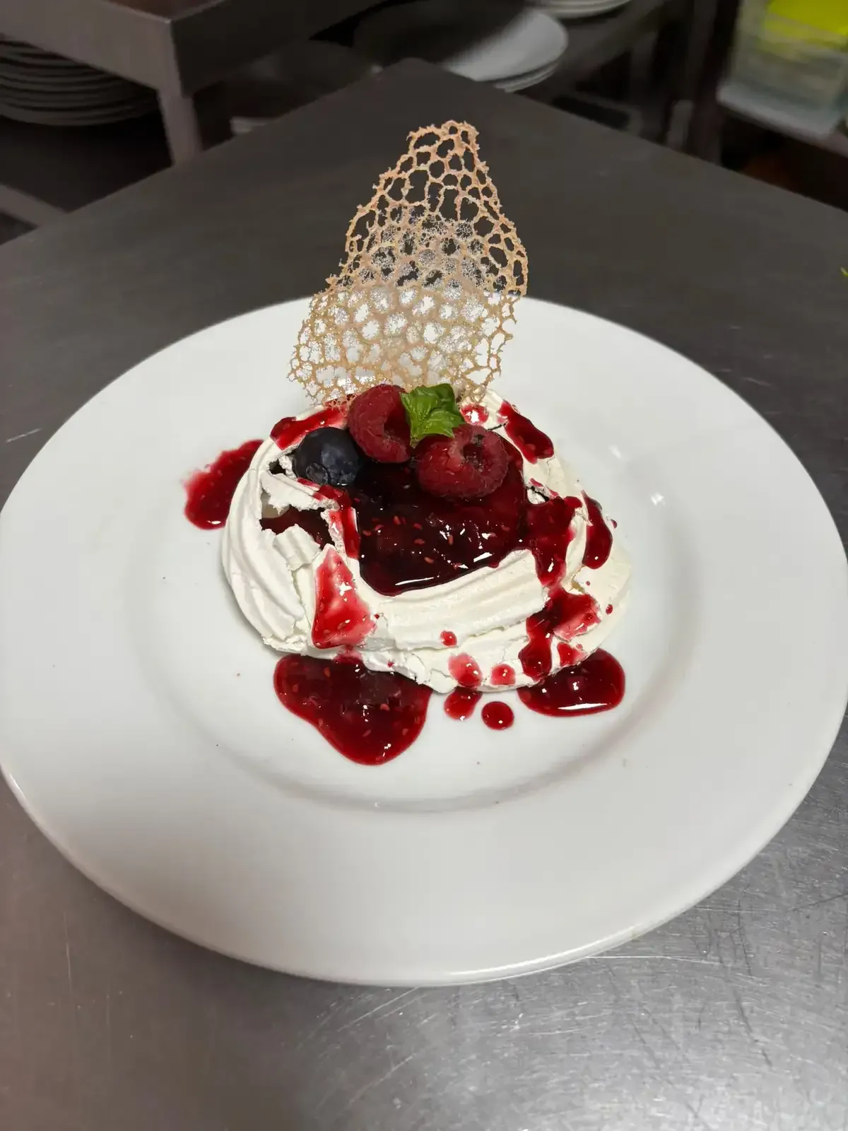Postre Pavlova con compota de bayas y guarnición en un plato blanco.