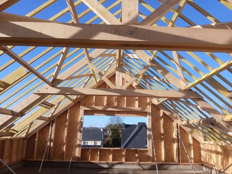 Vue de l'intérieur d'un grenier en construction, montrant les chevrons de charpente apparents et une grande ouverture de fenêtre.